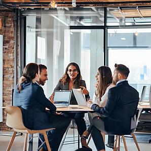 A group of sales people communicating around a desk  The Academy World